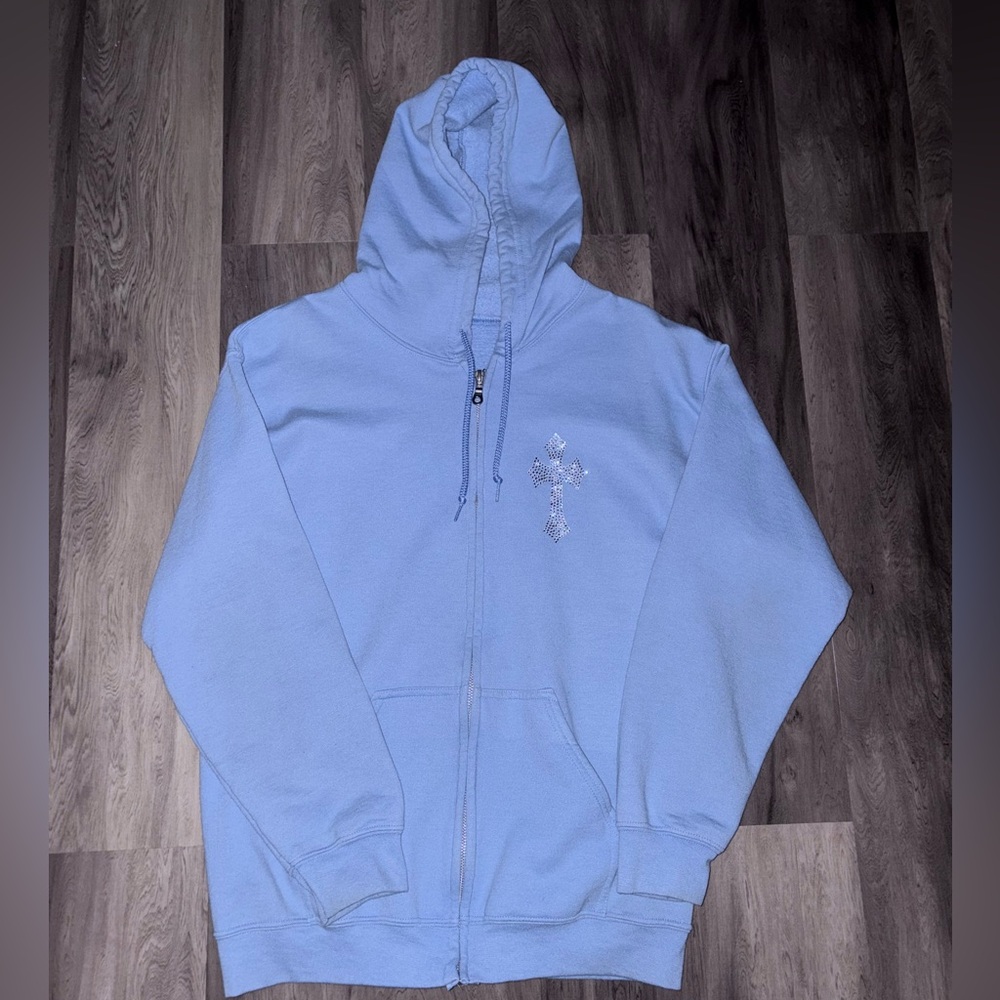 Baby blue zip-up hoodie with cross design on front, featuring a mix of cotton.